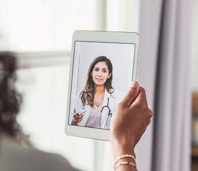 A female doctor offers an unrecognizable female patient advice during a telemedicine appointment.